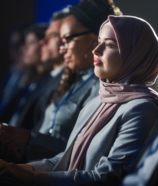 Arab,Female,Sitting,In,A,Dark,Crowded,Auditorium,At,A