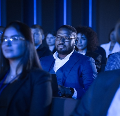 Black,Man,Sitting,In,A,Crowded,Audience,At,A,Business